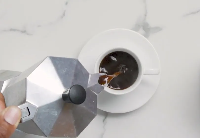 Pouring espresso coffee into a demitasse